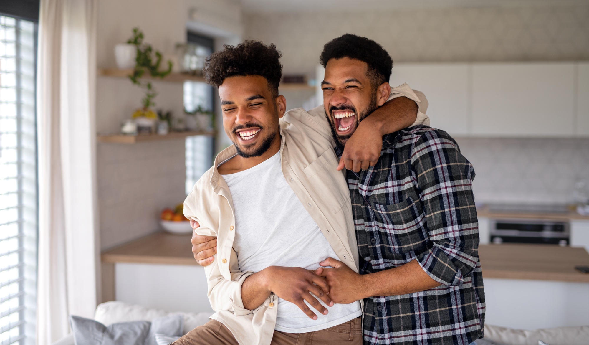 Young adult brothers in kitchen indoors at home, having fun